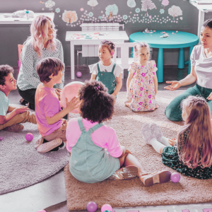 Parent and Child Groups. Photo of children and two adults playing on a carpet.